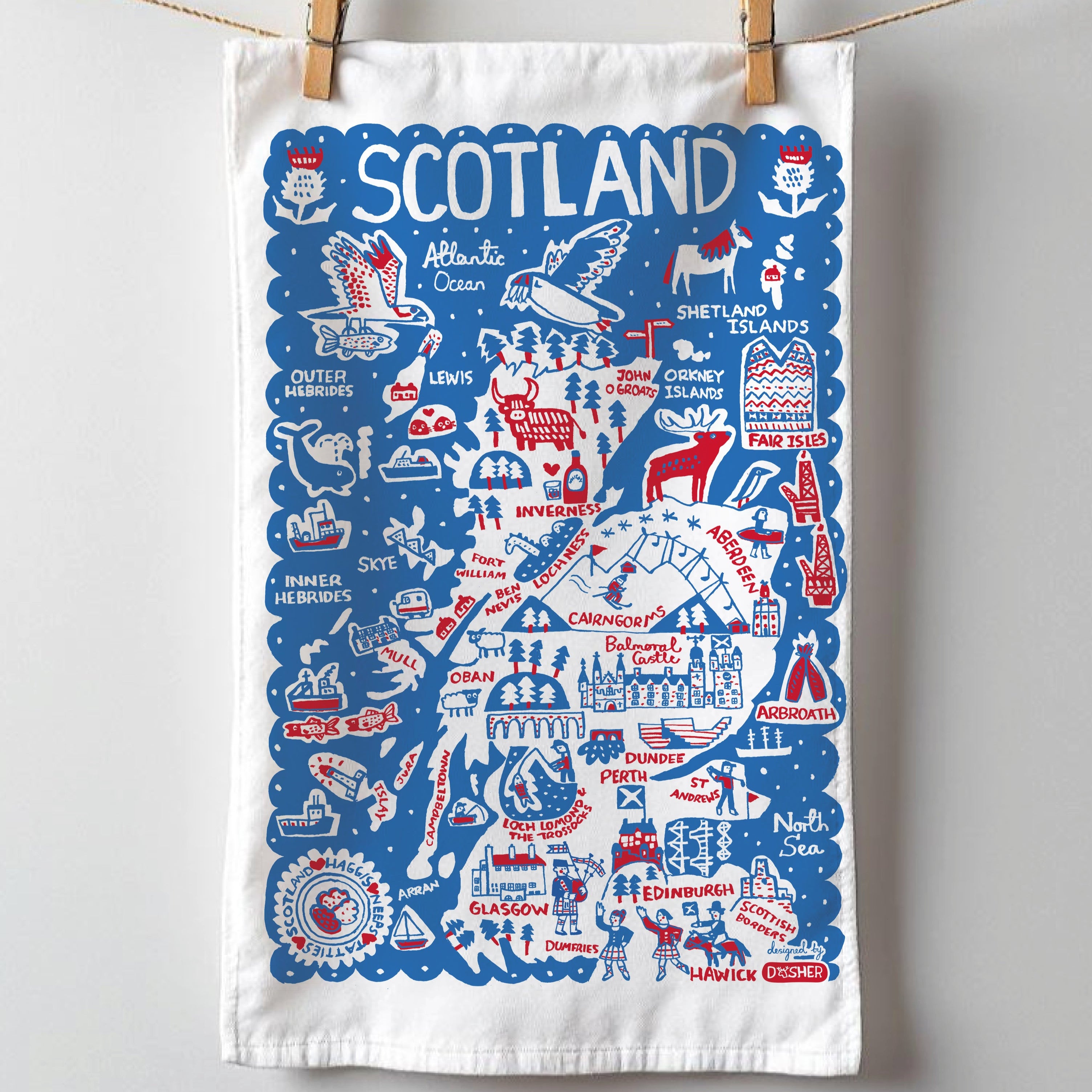 Tea towel with Scottish icons and text hanging on a line against a white background