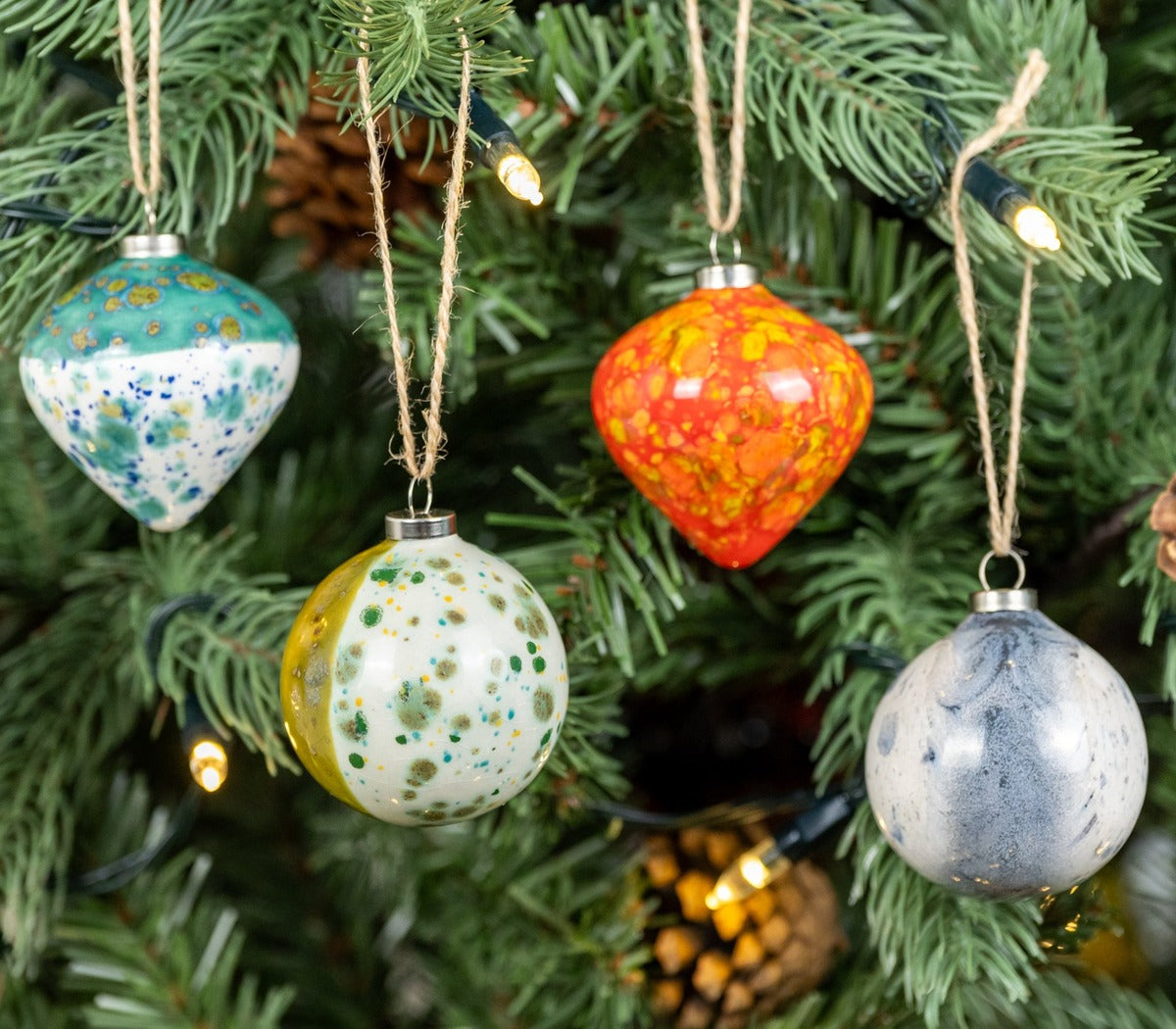 Green, red, grey and turquoise set of 4 baubles, diamond shape hanging on a christmas tree