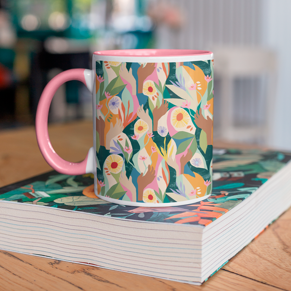 Front image of exclusive pink Unity mug designed by artist Lily Windsor Walker sat on a book