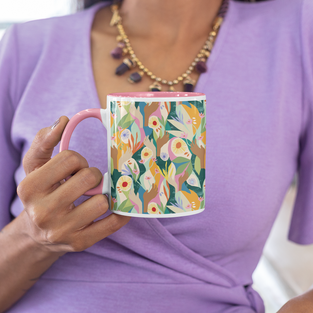 Front image of exclusive pink Unity mug designed by artist Lily Windsor Walker being held by a woman in a purple dress