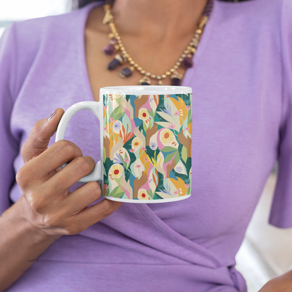 Front image of an exclusive Unity mug designed by artist Lily Windsor Walker being held by a woman in a purple dress