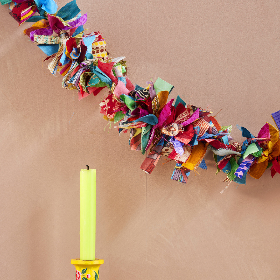 Colorful fabric wreath with a yellow candle on a beige background