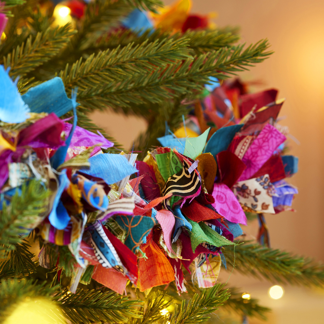 Colorful paper decorations on a Christmas tree with a warm glow in the background